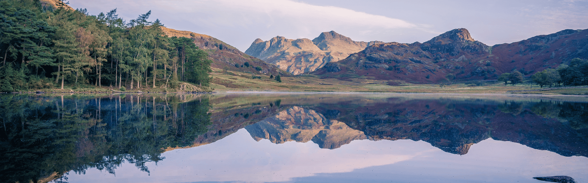 Un lac avec des arbres et de montagnes qui se reflètent dedans